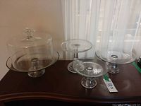 All four glass pedestal cake stands, dome on largest