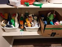Shelf with two white plastic bins and a cardboard box filled with assorted cleaning and laundry products