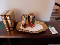 Group view showing two decorative book blocks, gold ceramic tray and two metallic candles