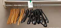 Wood and black plastic hangers on closet rod