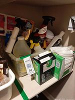 Shelf with cleaning products, Swiffer cloth box, loose cloth stack, various spray bottles, garbage bag box