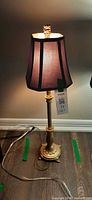 Full view of lit gold-tone table lamp with shade