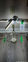 LED desk lamp illuminated resting on clear glass table lamp base