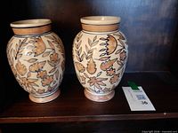 Front view of both matching ceramic vases on shelf