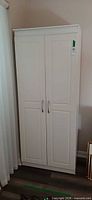 Front view of tall white utility storage cabinet with double panel doors and handles