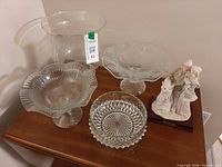 Group view of figurine, hurricane vase, three candy dishes on table