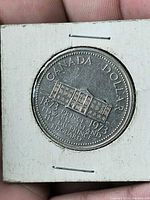 Reverse of coin in flip showing Province House and commemorative dates