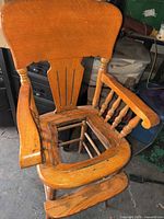 front angled view of commode chair showing missing seat insert and spindle arms