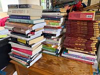 Three stacks of assorted books on wooden surface