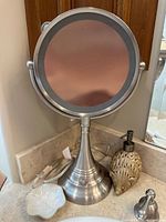 Front of lighted makeup mirror with shell dish and porcupine dispenser