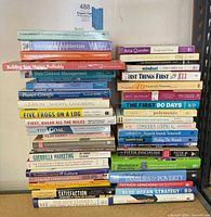 Two tall stacks of assorted business and self-improvement books showing spines and titles