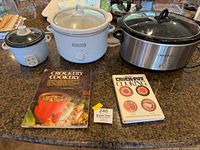 Group shot of three cookers and two cookbooks on countertop