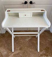 Front view of white folding desk with raised shelf and drawer