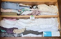 Cabinet shelves filled with folded sheets in assorted colors and a mattress protector box