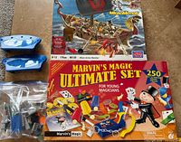 Boxes of Marvin’s Magic Ultimate Set and Mega Bloks King Arthur Warship, two blue boat hull pieces, bag of mixed LEGO bricks