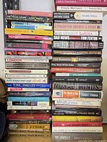 Three tall stacks of assorted books displaying spines for title identification