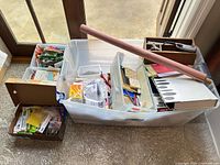 Wide view of entire plastic bin overflowing with assorted office supplies
