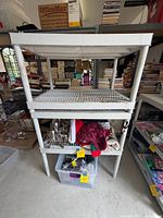 Front view of white plastic shelving unit showing three slatted shelves and overall structure