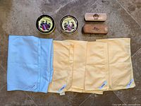 Top view of both wax tins, six cloths and two brushes displayed on floor