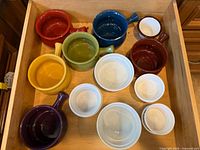 Drawer with six colourful soup crocks and six white ramekins