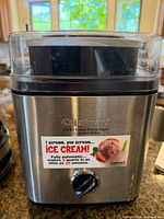 Front view of stainless steel Cuisinart ice cream maker showing brand, capacity and control knob