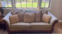 Full view of upholstered sofa with pillows and carved wood base