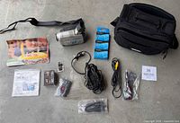 Camcorder, accessories, tapes, manuals and bag laid out on floor