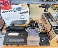 Group shot showing both Sanyo transcribers (boxed and unboxed), Sony recorders in cardboard box, blank cassettes, pedals, pouches and cables