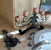Five-light wrought iron candelabra with candles and scroll wall sconce on countertop