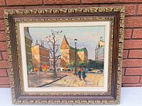 Framed Levarts oil painting depicting cityscape, ornate carved frame visible