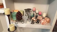Shelf displaying entire assortment of candles, salt holders, iron stands and decorative holders