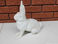 Side view of white cast iron rabbit statue showing overall form and condition