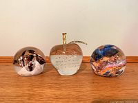 Front view of three glass paperweights showing their shapes and internal designs