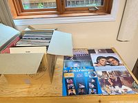 Box filled with vinyl LPs and several records laid out on table
