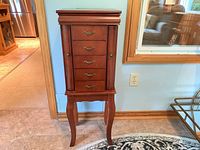 Front view of cherry-tone wood jewelry armoire on cabriole legs