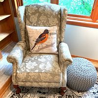 Front view of La-Z-Boy floral wingback recliner with bird pillow and grey pouf