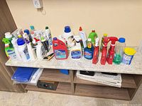 Full lot of cleaning supply bottles and jugs on countertop