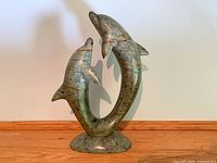 Front view of polished soapstone sculpture showing two dolphins in circular pose