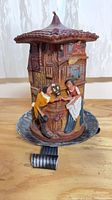 Front view of wax candle on metal holder showing man offering flowers to woman