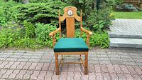 Front view showing full chair, wood finish, green seat, crest medallion