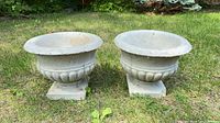 Front view of both matching concrete urn planters on grass