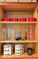 cabinet overview showing red crocks, assorted glasses, soup bowls, mug