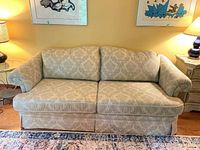 Front view of cream and grey patterned sofa with two seat and back cushions showing rolled arms and skirt