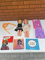 Lot overview showing two dolls, jump rope, three books, two notebooks