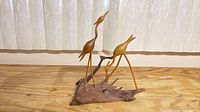 Full view of carved wooden sculpture with two herons on driftwood base