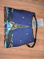 Front view of navy canvas shoulder bag showing Eiffel Tower graphic and faux leather strap