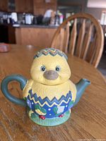 Front view of ceramic chick teapot showing facial details, handle and spout