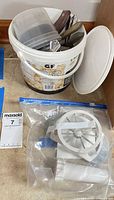 Bucket with plastic containers, wood-handled knives, spoons, forks beside bagged slicer