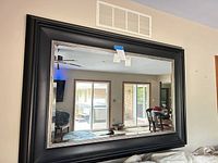 Front view of the large black-framed mirror mounted on wall