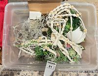 Plastic tote containing macrame planters, faux succulents, LED star lights